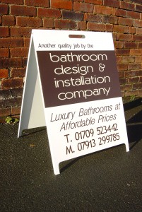 A board sign in front of a brick wall