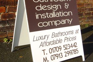 A board sign in front of a brick wall