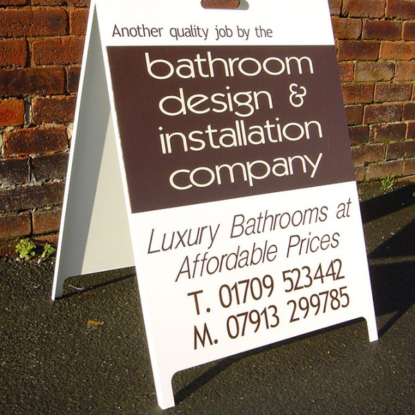 A board sign in front of a brick wall